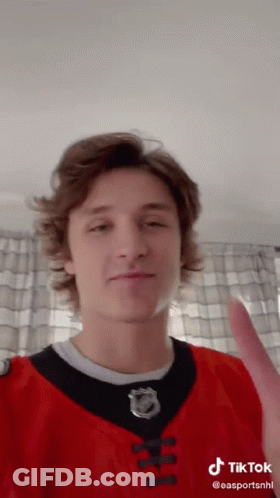 A Young Man Wearing A Red And Black Jersey With A Nhl Logo On It GIF