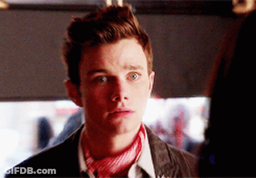 A Young Man Wearing A Red And White Scarf Looks At The Camera GIF