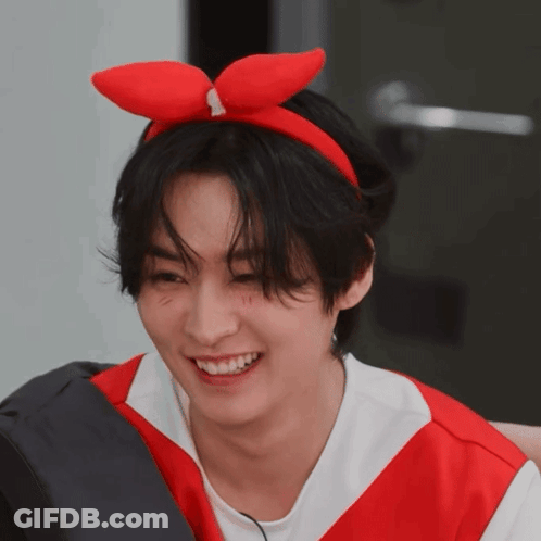 A Young Man Wearing A Red Bow On His Head Smiles GIF