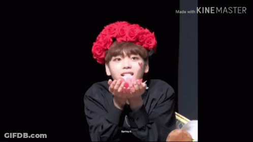 A Young Man Wearing A Red Flower Crown Is Blowing Petals In The Air . GIF