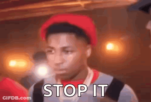 A Young Man Wearing A Red Hat And A Backpack Is Standing In Front Of A Crowd . GIF