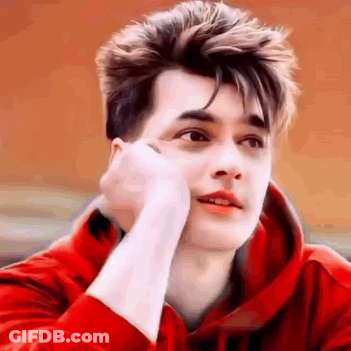 A Young Man Wearing A Red Hoodie Is Looking At The Camera . GIF