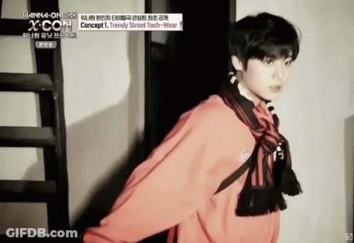 A Young Man Wearing A Red Jacket And Scarf Is Standing Next To A Staircase . GIF