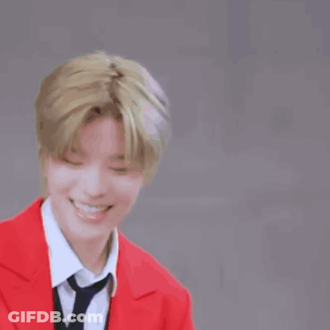 A Young Man Wearing A Red Jacket And Tie Is Smiling . GIF