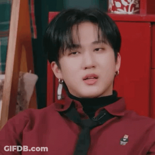 A Young Man Wearing A Red Shirt And A Black Tie Is Making A Funny Face . GIF