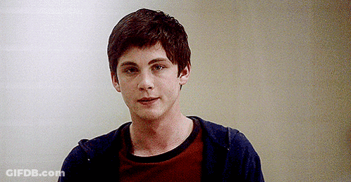 A Young Man Wearing A Red Shirt And A Blue Hoodie Is Standing In Front Of A Wall . GIF
