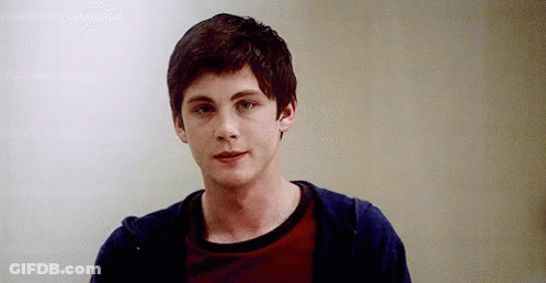 A Young Man Wearing A Red Shirt And A Blue Hoodie Is Standing In Front Of A White Wall . GIF