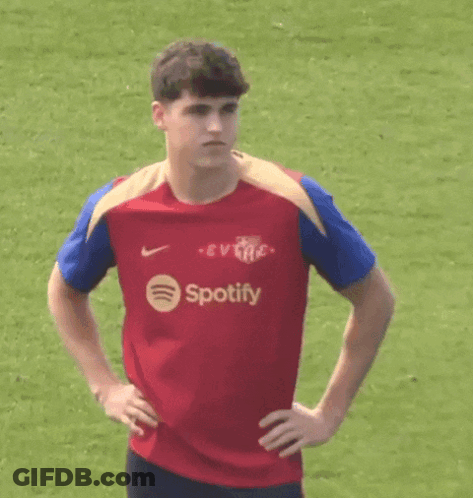 A Young Man Wearing A Red Spotify Shirt Is Standing On A Field . GIF