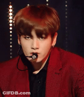 A Young Man Wearing A Red Suit And A Microphone In His Mouth GIF