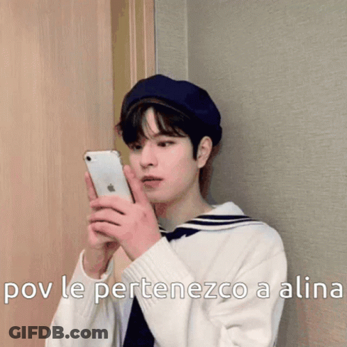 A Young Man Wearing A Sailor Hat Is Holding A Cell Phone . GIF