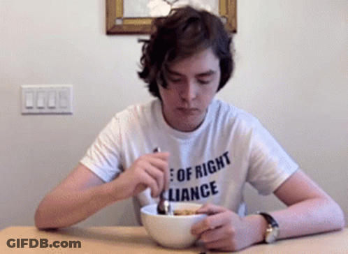 A Young Man Wearing A Shirt That Says " Of Right Alliance " Is Eating Cereal GIF