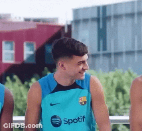 A Young Man Wearing A Spotify Shirt Is Smiling While Standing Next To A Group Of Young Men . GIF