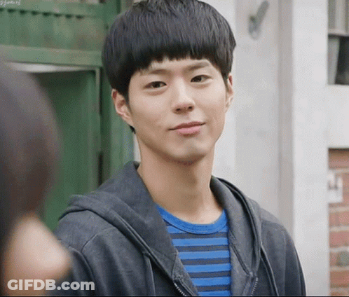 A Young Man Wearing A Striped Shirt And A Black Jacket Looks At The Camera GIF