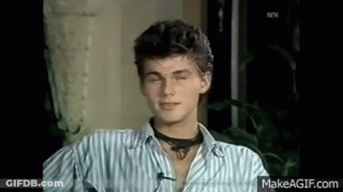 A Young Man Wearing A Striped Shirt And A Choker Is Sitting In A Chair With His Eyes Closed . GIF