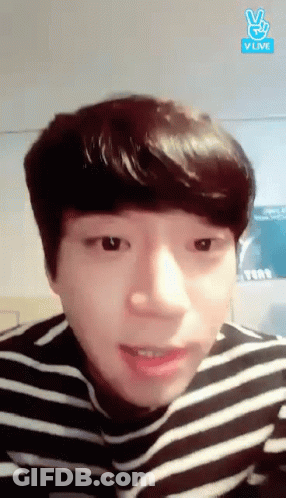 A Young Man Wearing A Striped Shirt Is Making A Peace Sign GIF