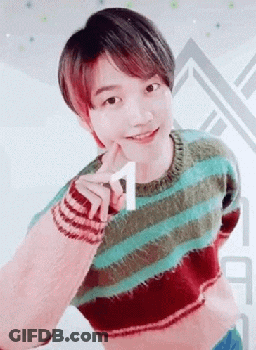A Young Man Wearing A Striped Sweater Is Making A Heart Shape With His Hand . GIF