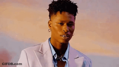 A Young Man Wearing A Suit And Earrings Is Looking At The Camera With His Mouth Open . GIF