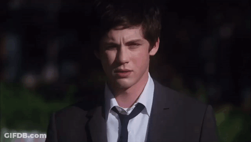 A Young Man Wearing A Suit And Tie Looks At The Camera GIF