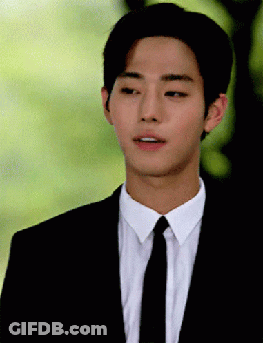 A Young Man Wearing A Suit And Tie Looks To His Left GIF