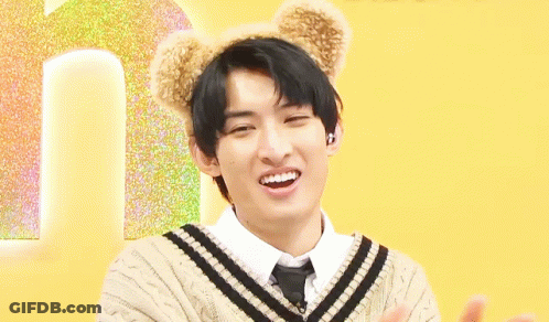 A Young Man Wearing A Sweater And Tie With Teddy Bear Ears On His Head Is Smiling . GIF