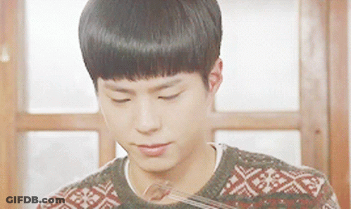 A Young Man Wearing A Sweater Is Eating A Piece Of Food GIF