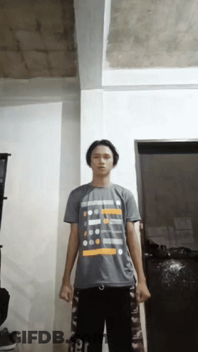 A Young Man Wearing A T-Shirt That Says ' Happiness ' On It Stands In A Room GIF