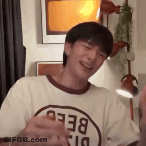 A Young Man Wearing A T-Shirt With The Word Bee On It Is Laughing While Standing In A Room . GIF