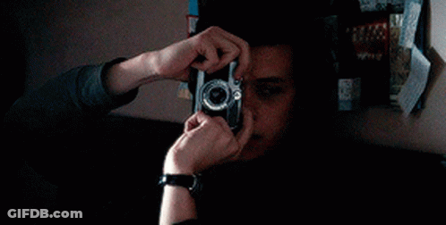 A Young Man Wearing A Watch Is Playing A Video Game In A Dark Room . GIF