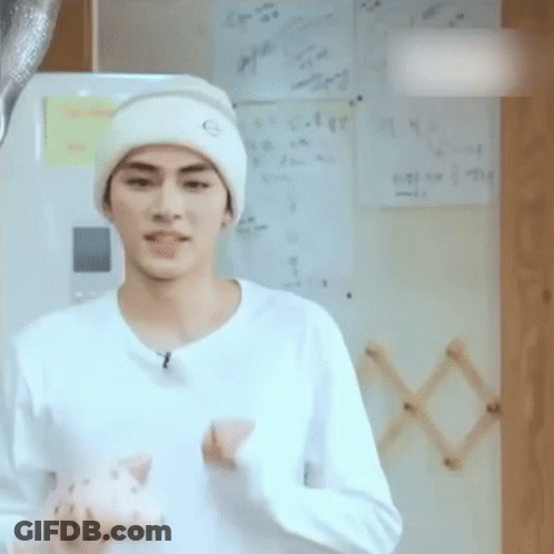 A Young Man Wearing A White Hat And A White Shirt Is Holding A Stuffed Animal . GIF