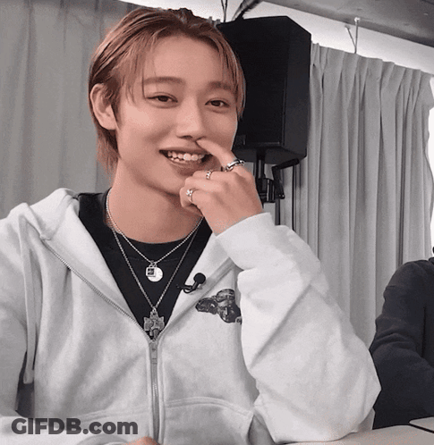 A Young Man Wearing A White Hoodie And A Necklace With The Letter R On It GIF