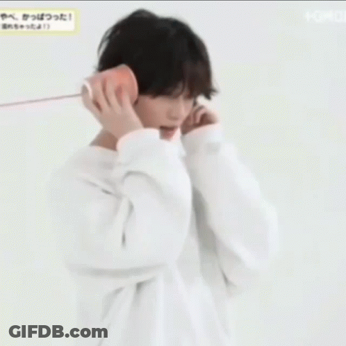 A Young Man Wearing A White Hoodie Is Talking On A Cell Phone . GIF