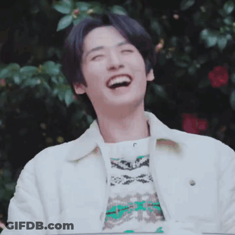 A Young Man Wearing A White Jacket And A Sweater Is Laughing With His Eyes Closed . GIF