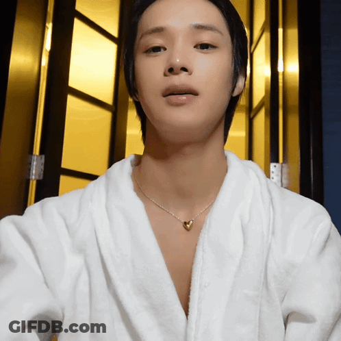 A Young Man Wearing A White Robe And A Heart Necklace GIF
