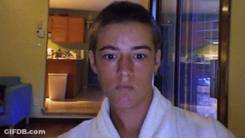 A Young Man Wearing A White Robe Is Making A Funny Face GIF