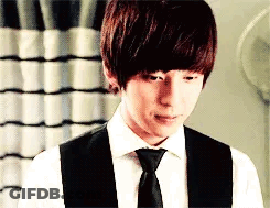 A Young Man Wearing A White Shirt And Black Vest And Tie . GIF