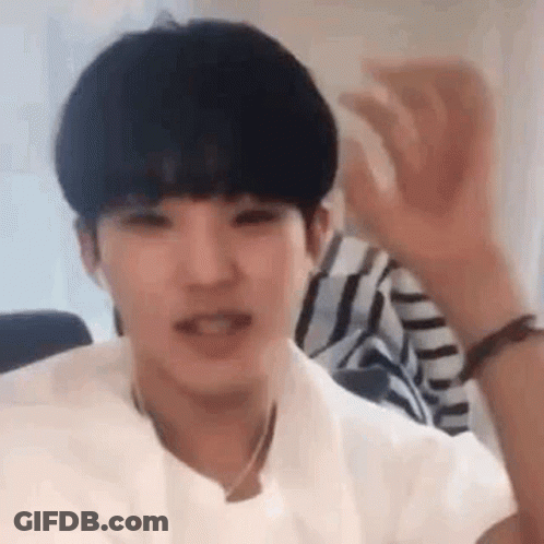 A Young Man Wearing A White Shirt Is Waving His Hand In The Air . GIF
