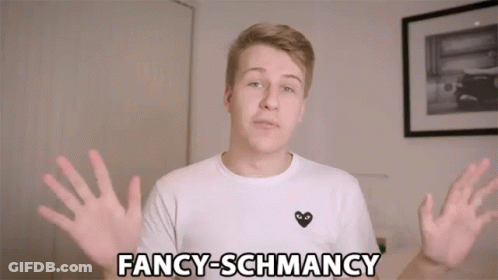 A Young Man Wearing A White Shirt With A Black Heart On It Says Fancy-Schmancy GIF