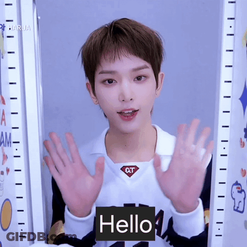 A Young Man Wearing A White Shirt With The Word Qt On It Says Hello GIF