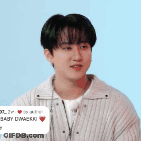 A Young Man Wearing A White Sweater And A Necklace Has A Sticker On His Neck That Says Baby Dwaekki GIF