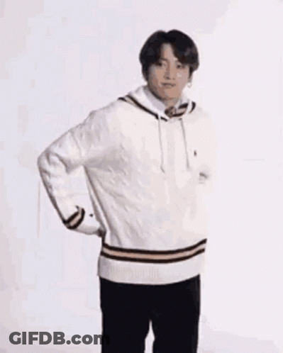 A Young Man Wearing A White Sweater And Black Pants Is Standing On One Leg . GIF