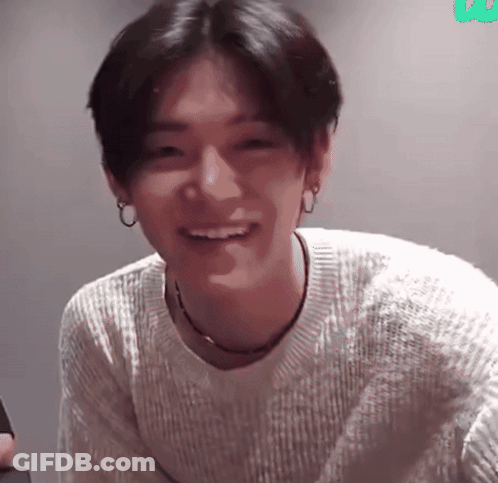 A Young Man Wearing A White Sweater Is Smiling GIF