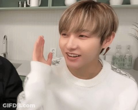 A Young Man Wearing A White Sweater Is Waving His Hand GIF