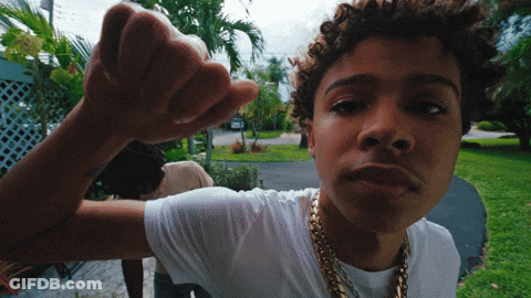 A Young Man Wearing A White T-Shirt And Gold Chains Is Making A Fist GIF