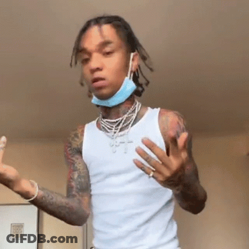 A Young Man Wearing A White Tank Top And A Blue Face Mask Is Standing In A Room . GIF