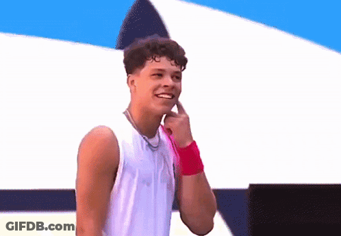 A Young Man Wearing A White Tank Top And A Pink Wristband Smiles GIF