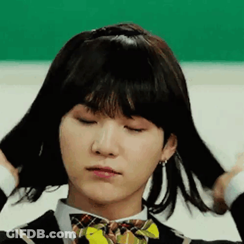 A Young Man Wearing A Wig And A Bow Tie Is Making A Funny Face . GIF