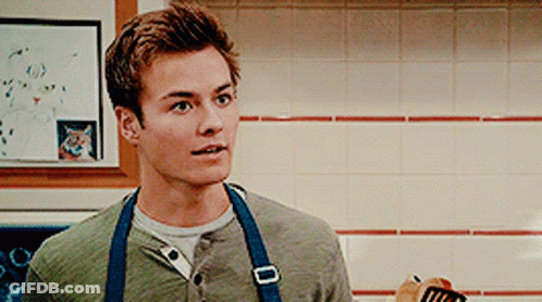A Young Man Wearing An Apron Is Holding A Spatula GIF