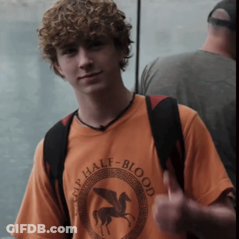 A Young Man Wearing An Orange Shirt That Says Camp Half-Blood Giving A Thumbs Up GIF