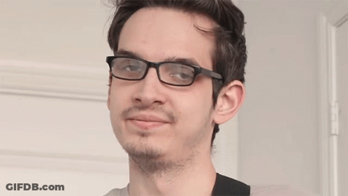 A Young Man Wearing Glasses And A Beard Looks At The Camera GIF