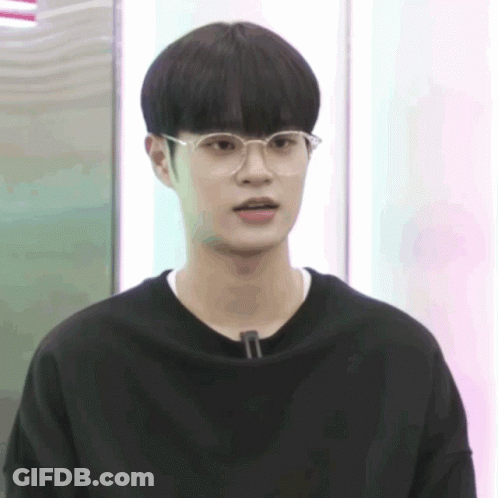 A Young Man Wearing Glasses And A Black Shirt Is Looking At The Camera GIF